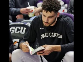 Gabe McGlothan of the Grand Canyon University Antelopes reads the Bible on the bench before games.