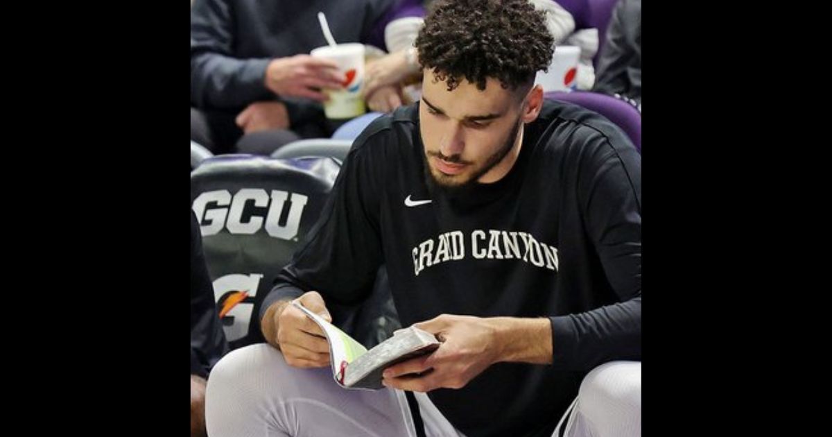 Gabe McGlothan of the Grand Canyon University Antelopes reads the Bible on the bench before games.