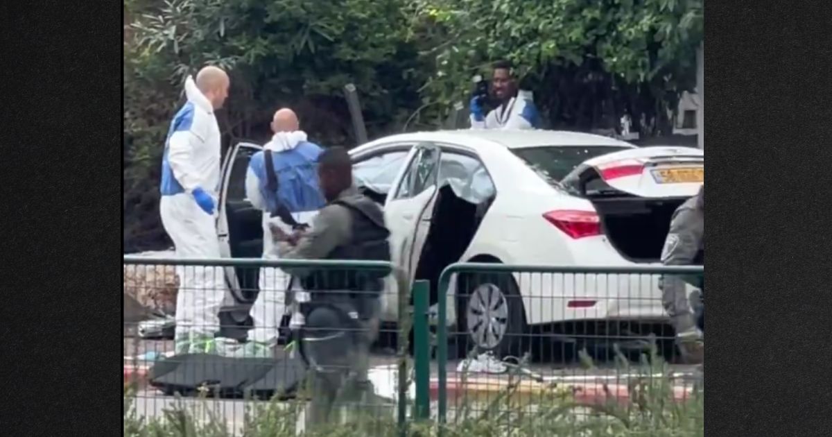 Investigators examine one of the carjacked vehicles used in the attack while armed soldiers stand by.