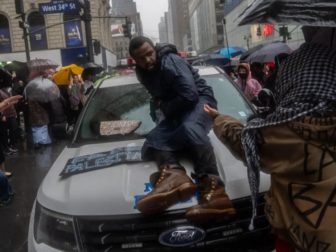 A pro-Hamas demonstrator sits on the hood of a New York City police vehicle that's surrounded by Hamas sympathizers Saturday in Manhattan.