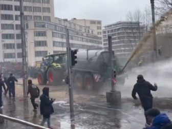 During a protest last week in Brussels, Belgium, farm vehicle sprays liquid manure while a police water cannon tries to disperse the waste.
