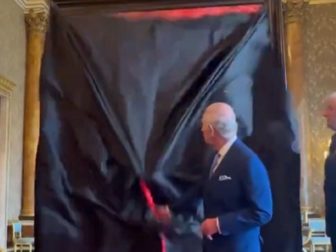 The U.K.'s King Charles III unveils a portrait of himself on Tuesday in London.